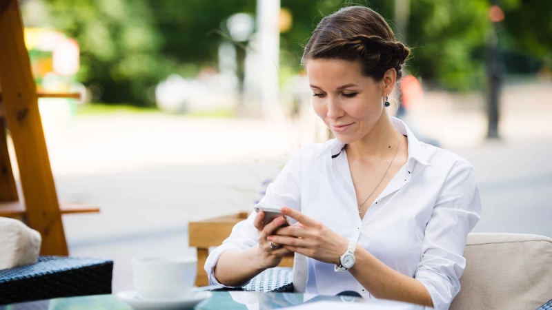 Portrait of a charming business woman chatting on her smart phone while waiting someone in cafe
